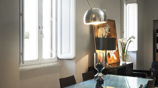 Sala da pranzo con grande finestra, lampada a sospensione e opera d'arte. Ristrutturazione Trieste Roma. (Progetto Perla Decò)